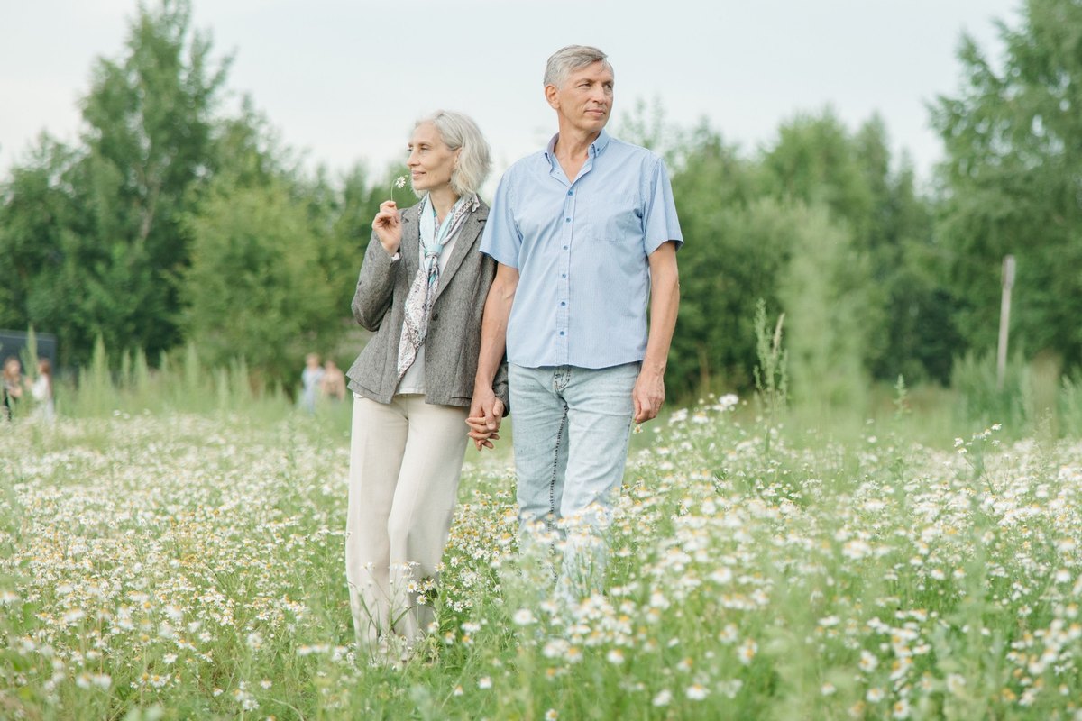 Older couple holding hands in a meadow of white daisies