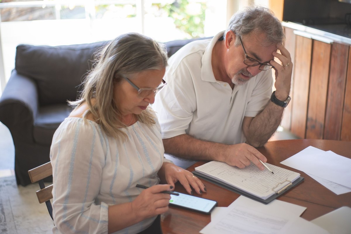 Man and woman going over papers, a notebook, and a phone at a wooden table