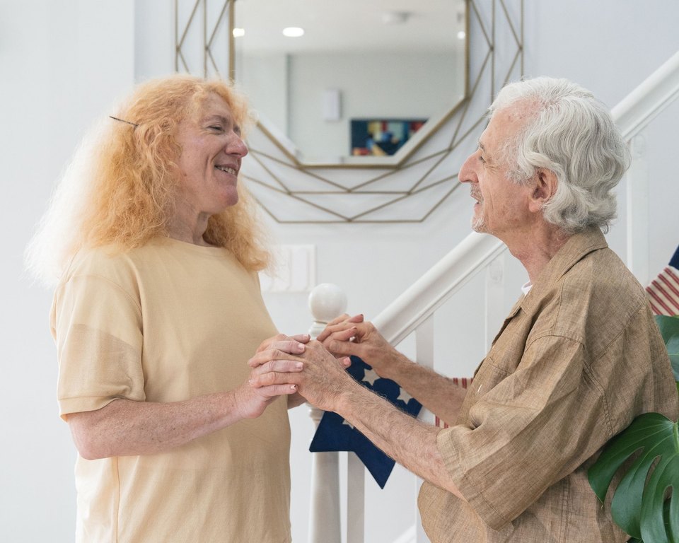 Man and woman standing face to face and holding hands at the foot of a staircase