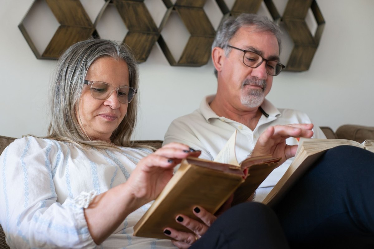 Man and woman reading old books side by side on a couch