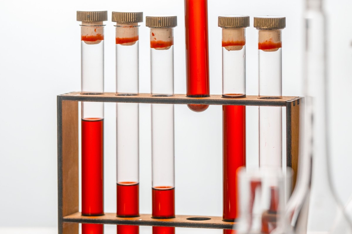 Glass test tubes with red liquid standing in a wooden rack