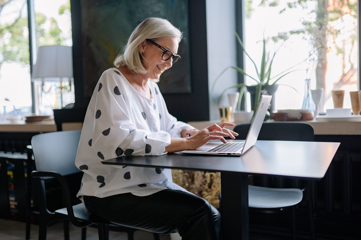 Woman in a polka dot blouse typing on a laptop at a table