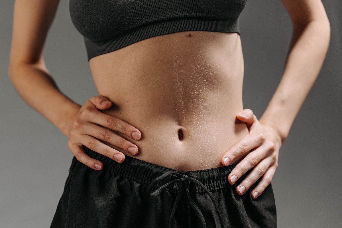 Woman in black athletic clothing with both hands on her hips, shown from chest to hips